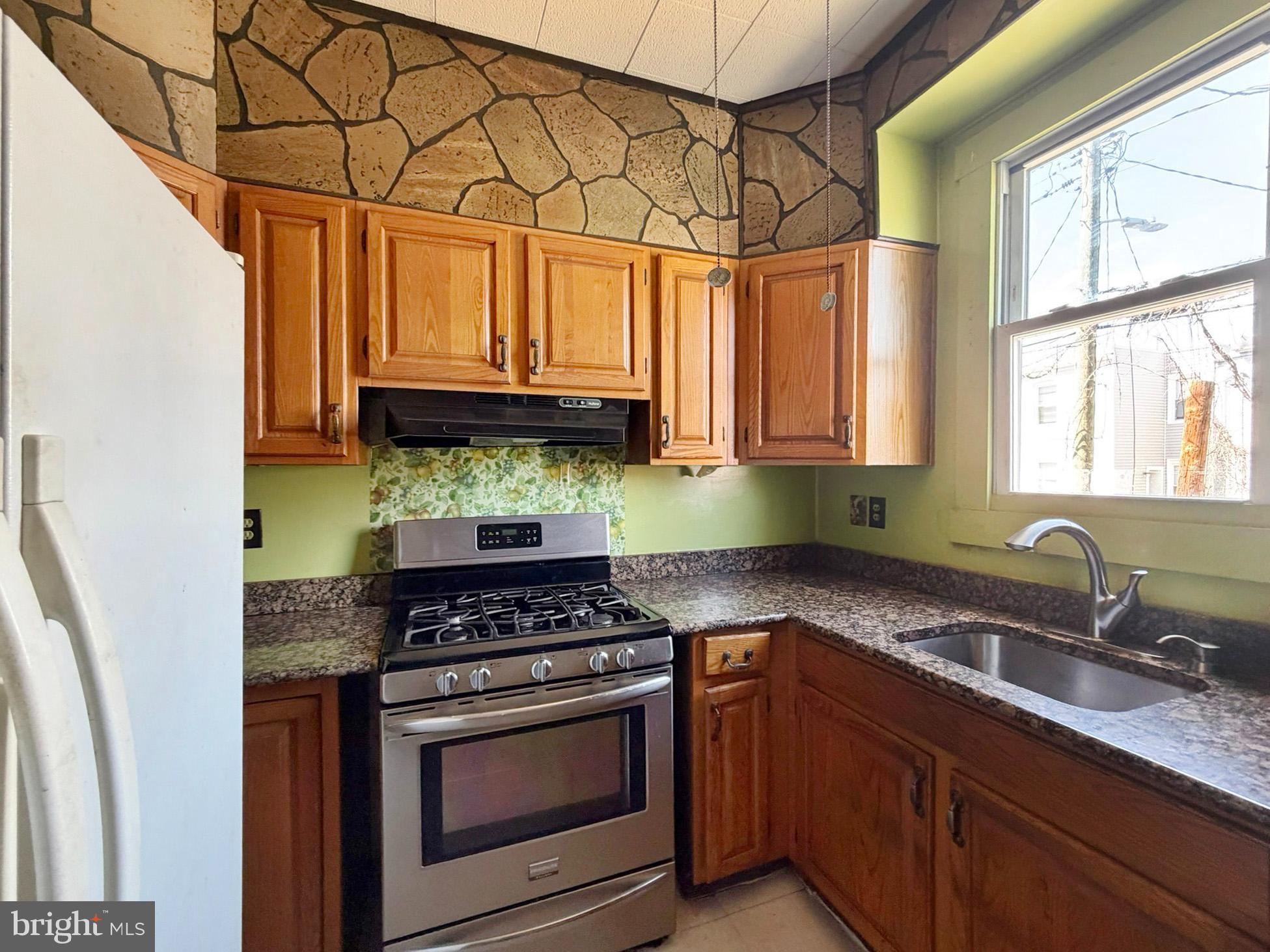 2802 Brighton Street Baltimore, MD 21216 - Photo 11 of 38 a kitchen with stainless steel appliances granite countertop a sink a stove and a microwave