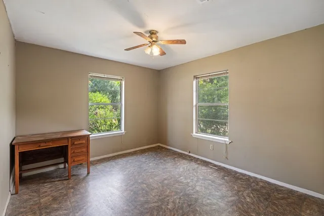 an empty room with windows and fan