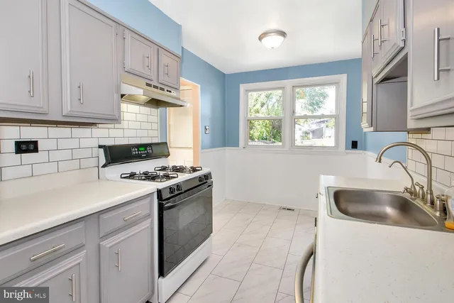 a kitchen with granite countertop a sink stove a refrigerator and cabinets