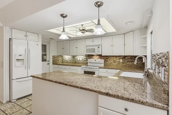 a kitchen with stainless steel appliances granite countertop a sink refrigerator and cabinets