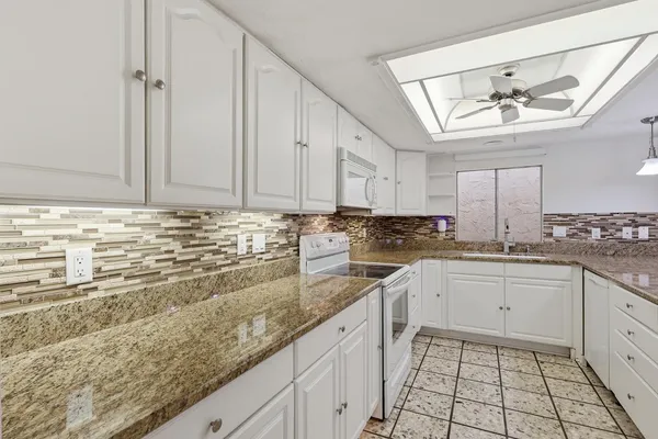 a kitchen with granite countertop white cabinets and white appliances