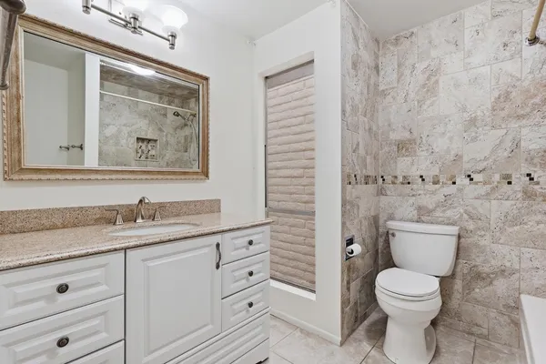 a bathroom with a granite countertop toilet sink and mirror