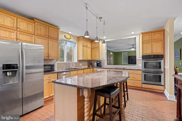 a view of a kitchen with kitchen island a counter top space a sink stainless steel appliances and cabinets