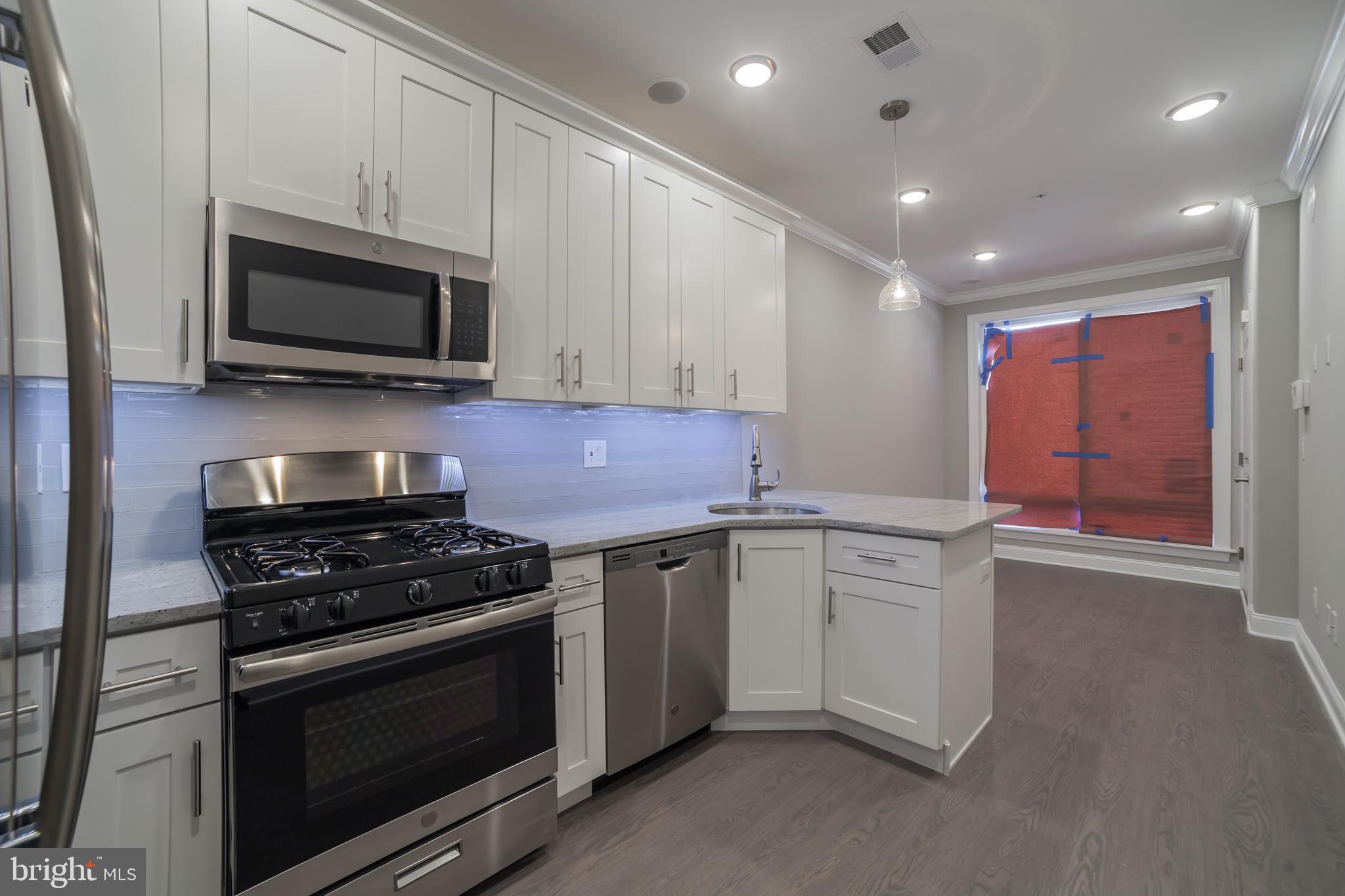 a kitchen with stainless steel appliances granite countertop a stove microwave and sink