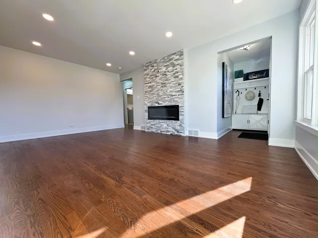 an empty room with wooden floor fireplace and windows