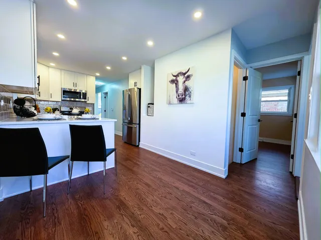 a kitchen with stainless steel appliances a dining table a stove a microwave and a refrigerator