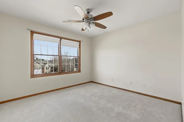 an empty room with ceiling fan and windows