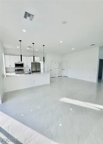 a large white kitchen with a large counter top and stainless steel appliances