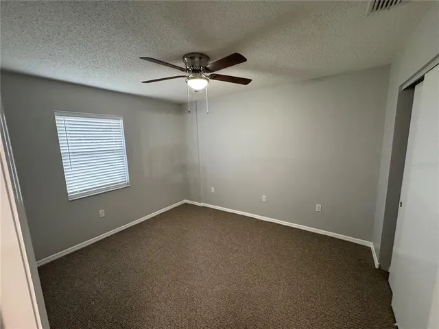 an empty room with a window and a fan