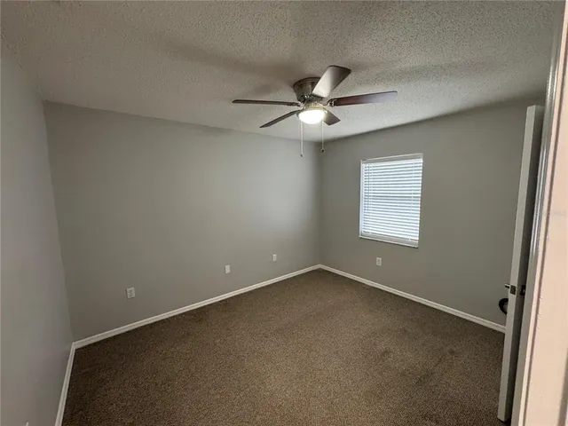 an empty room with a window and a fan