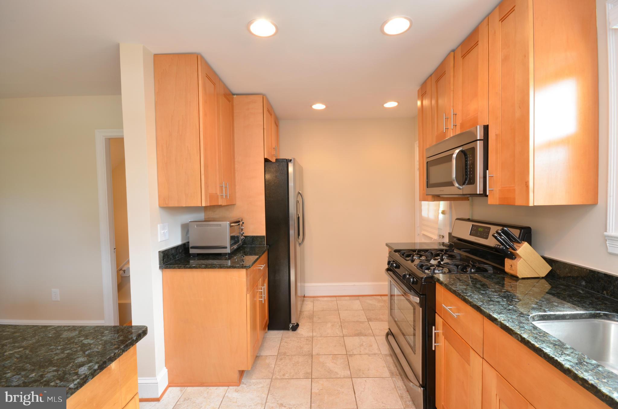 903 Forest Glen Road Silver Spring, MD 20901 - Photo 9 of 30 a kitchen with stainless steel appliances granite countertop a sink a stove and a refrigerator