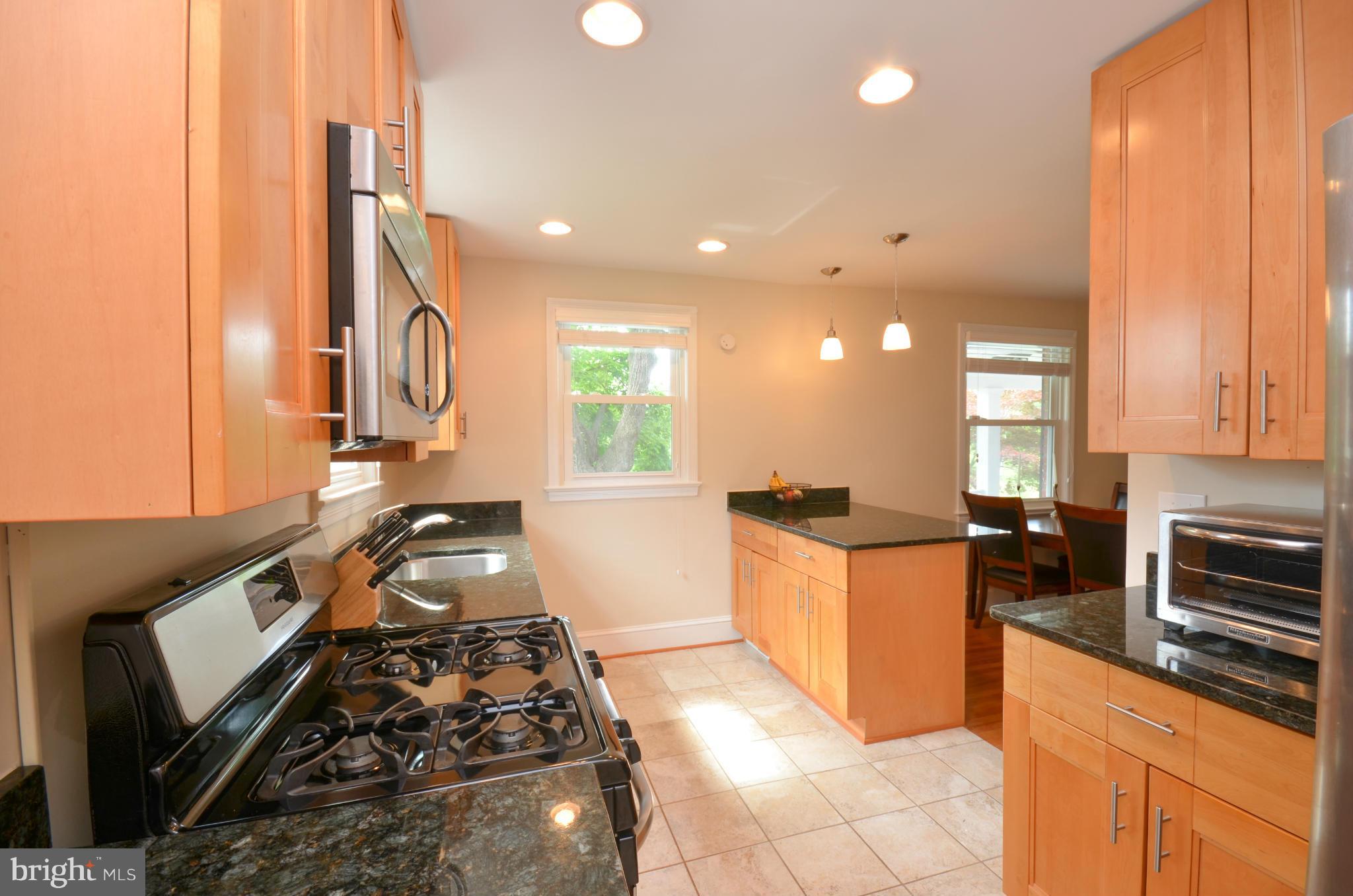 903 Forest Glen Road Silver Spring, MD 20901 - Photo 10 of 30 a kitchen with stainless steel appliances granite countertop a stove a sink and a microwave