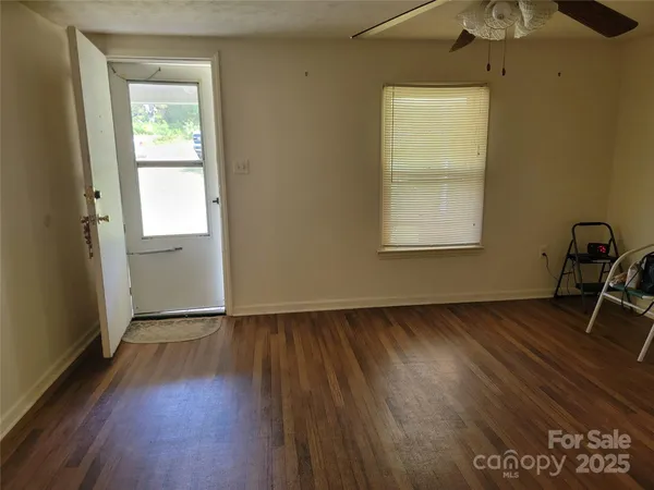 an empty room with wooden floor and windows