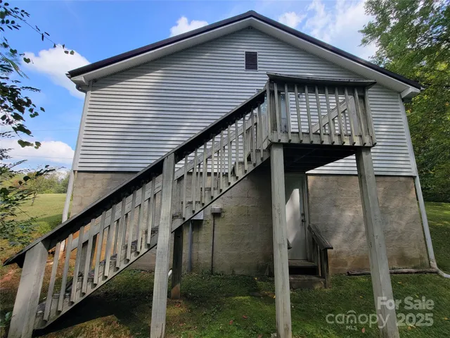 a view of house with wooden stairs and a small yard