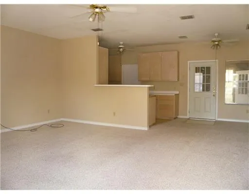 an empty room with chandelier fan and windows