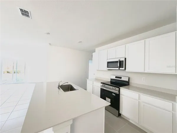 a kitchen with stainless steel appliances a stove a sink and white cabinets