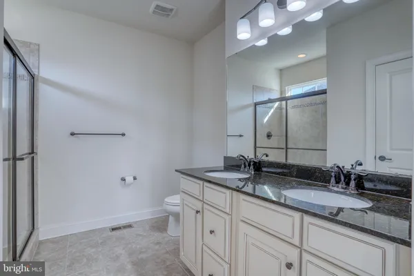 a bathroom with a granite countertop sink a toilet and a mirror