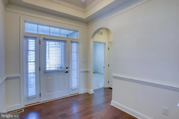 an empty room with wooden floor cabinet and windows