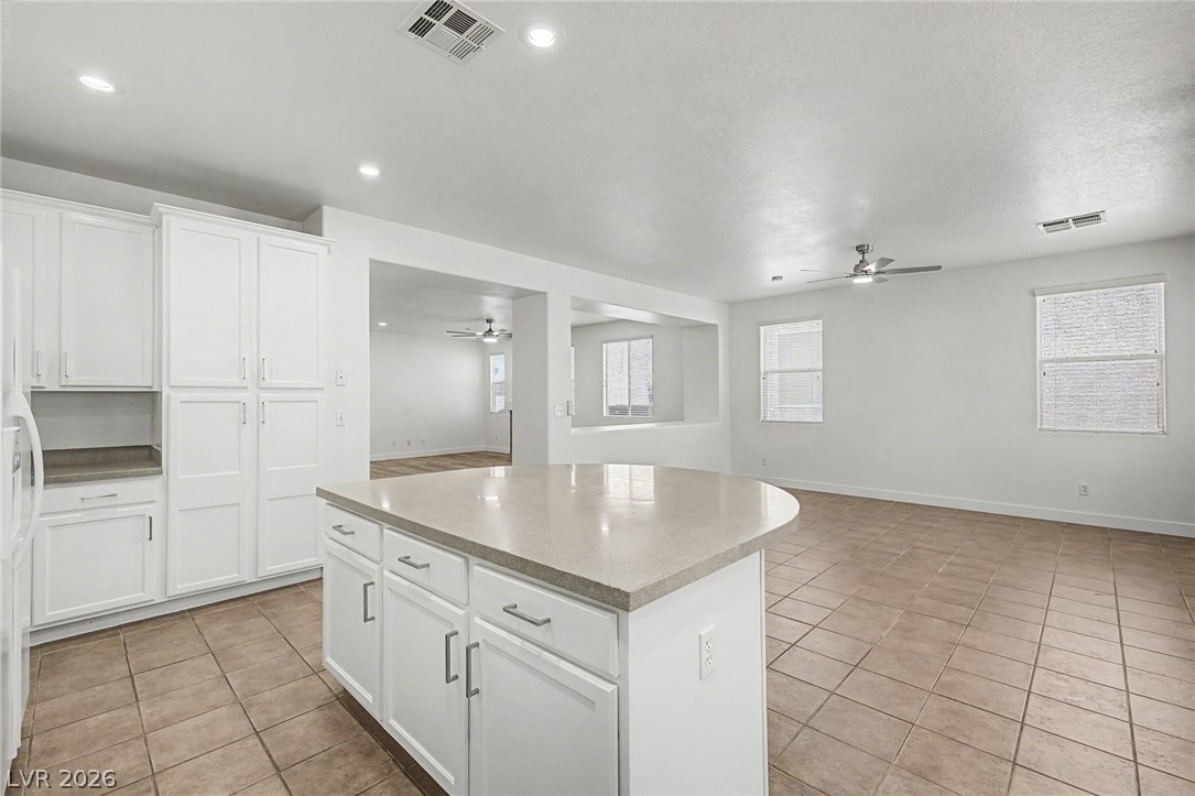 835 Entrada Ridge Avenue Henderson, NV 89012 - Photo 12 of 34 A well-lit kitchen with sleek white cabinetry and a large central island, seamlessly connecting to an inviting living area.