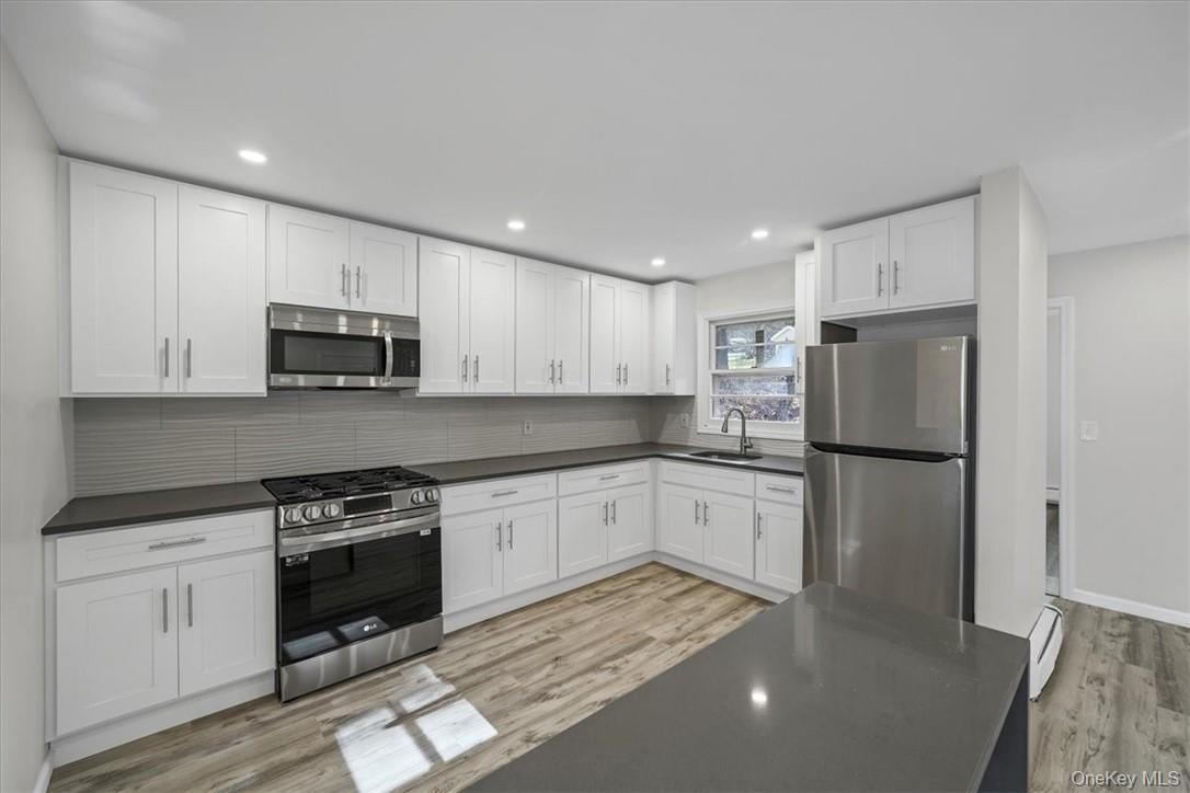 a kitchen with a refrigerator a stove top oven a sink and cabinets