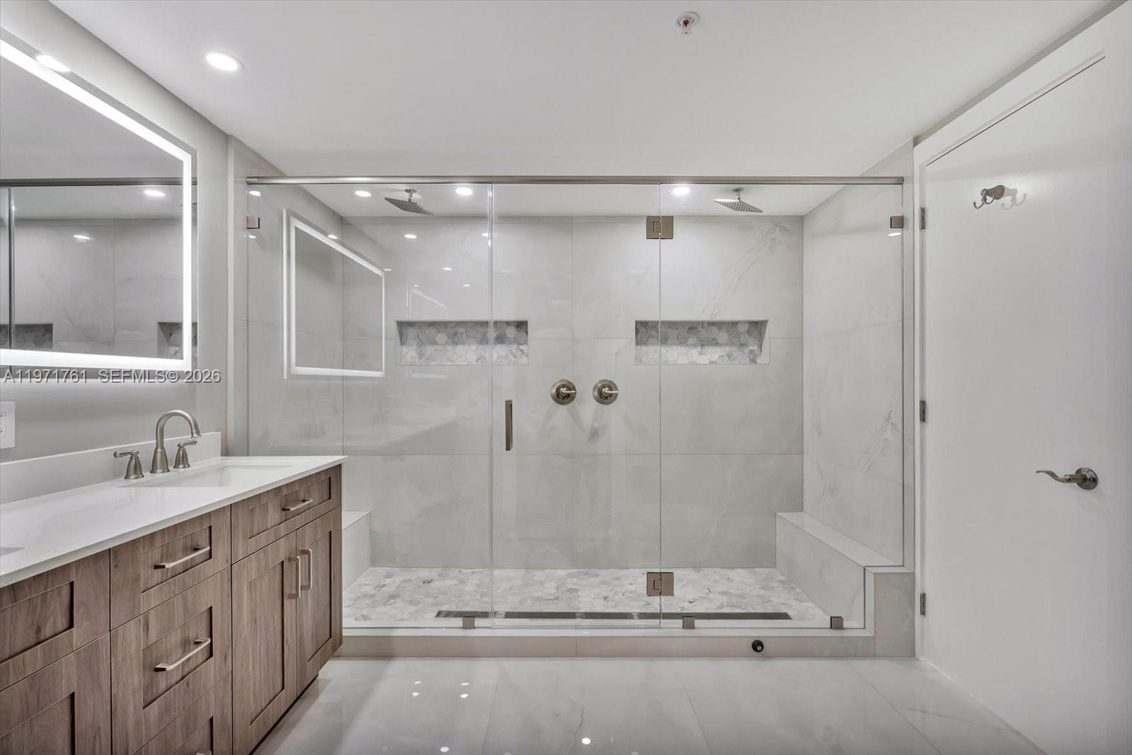 3400 Southwest 27th Avenue, Unit 602 Miami, FL 33133 - Photo 21 of 42 a bathroom with a granite countertop sink a mirror a shower and a bathtub
