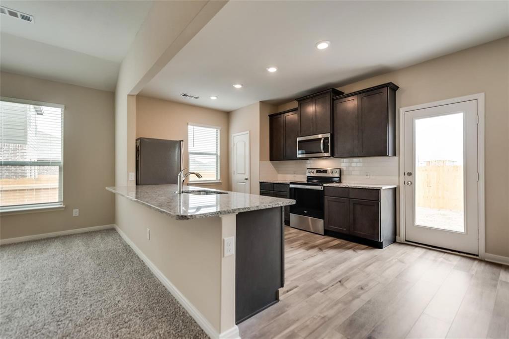 291 Wandering Stream Way Princeton, TX 75407 - Photo 8 of 22 a kitchen with kitchen island granite countertop a sink appliances and cabinets