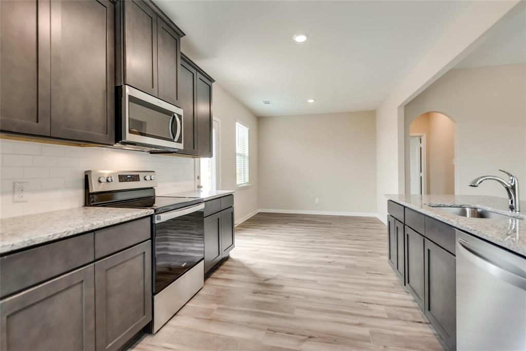 291 Wandering Stream Way Princeton, TX 75407 - Photo 9 of 22 a kitchen with stainless steel appliances granite countertop a stove a sink and a microwave