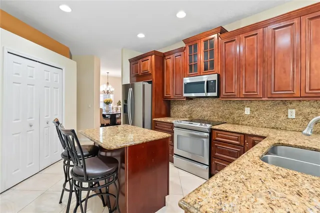 a kitchen with stainless steel appliances granite countertop wooden cabinets a dining table and chairs