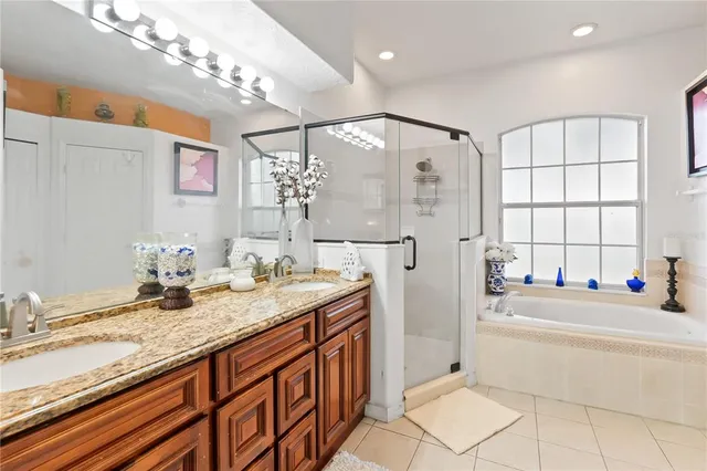 a bathroom with a granite countertop double vanity sink a mirror and a bathtub