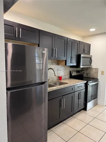 a kitchen with stainless steel appliances granite countertop a refrigerator and a stove top oven