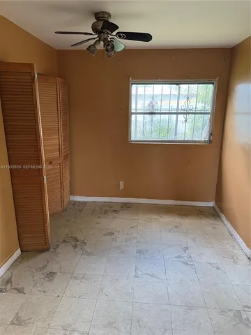 an empty room with windows and fan