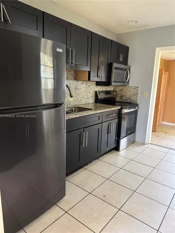 a kitchen with stainless steel appliances granite countertop a refrigerator a sink a stove top oven and a dishwasher