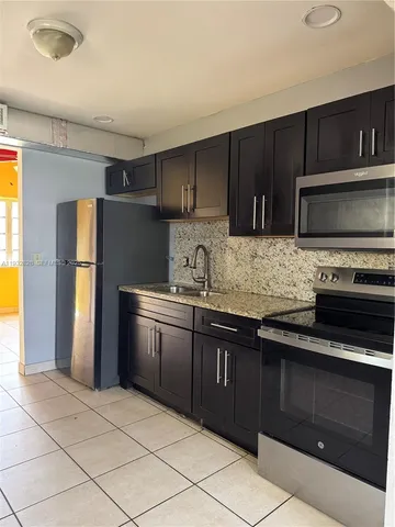 a kitchen with stainless steel appliances granite countertop a refrigerator and a stove top oven