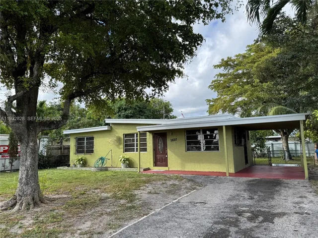 a view of a house with a yard and large tree