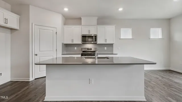 a kitchen with stainless steel appliances a sink a stove a refrigerator and cabinets