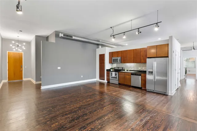 a large kitchen with a large counter top stainless steel appliances and wooden floor