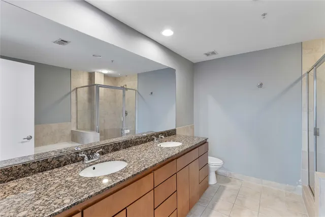 a bathroom with a granite countertop double vanity sink and a mirror