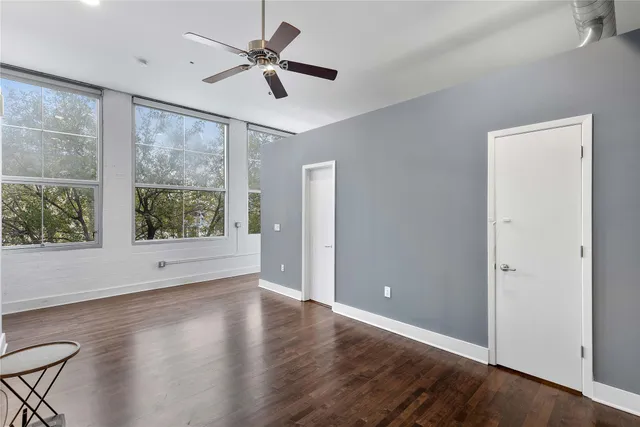 a view of empty room with wooden floor and fan