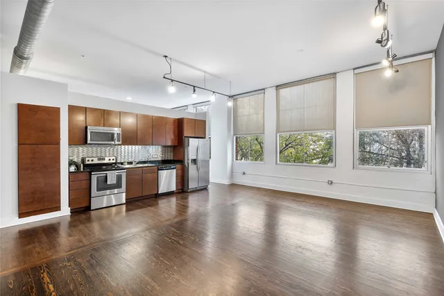 a large kitchen with a large counter top stainless steel appliances and wooden floor