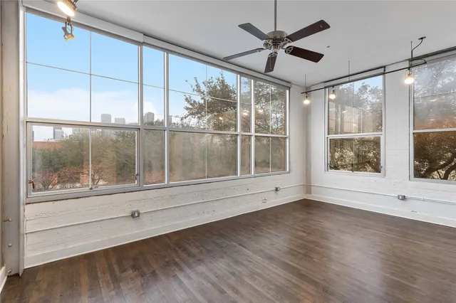 a view of an empty room with a window and wooden floor