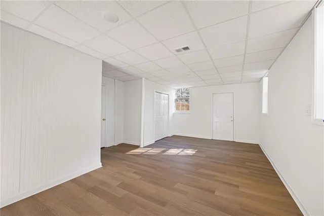 a view of an empty room with window and wooden floor