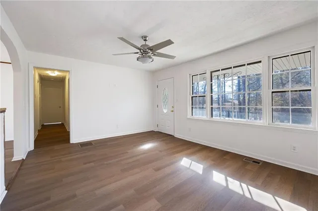 a view of an empty room with wooden floor and a window