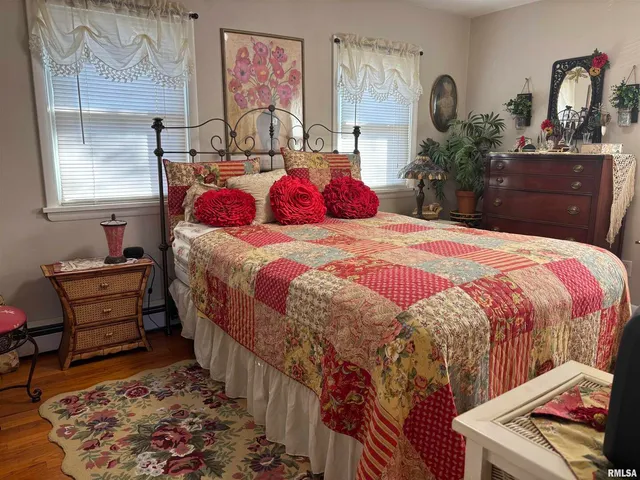 a bedroom with a bed and dresser with wooden floor