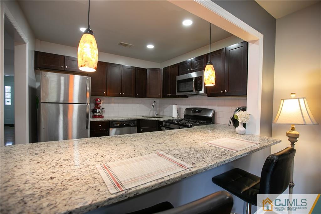 4308 Hana Road Edison, NJ 08817 - Photo 7 of 32 a kitchen with kitchen island granite countertop a sink appliances and cabinets