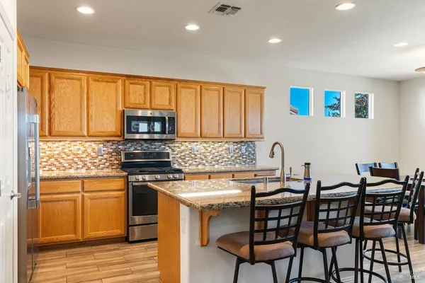 a kitchen with stainless steel appliances granite countertop a stove a sink and a microwave