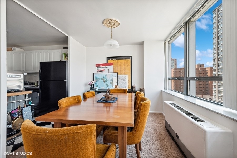 5701 North Sheridan Road, Unit 9L Chicago, IL 60660 - Photo 6 of 17 a kitchen with stainless steel appliances granite countertop a refrigerator a stove and a dining table with wooden floor