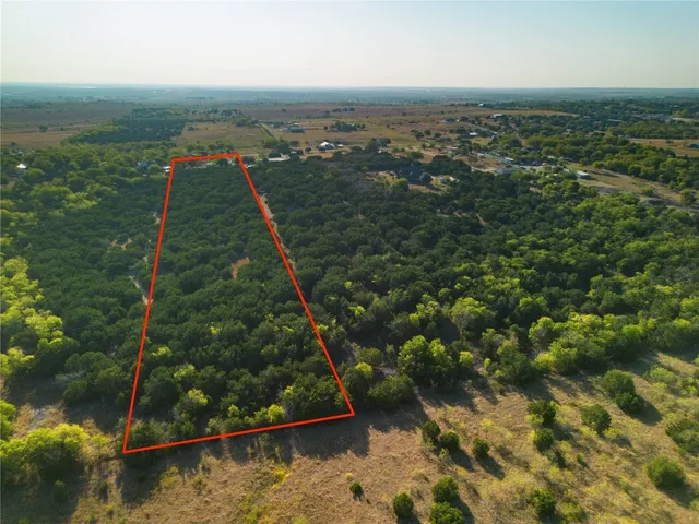 an aerial view of residential houses with outdoor space and trees
