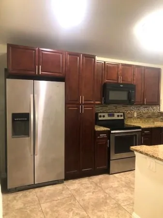 a kitchen with granite countertop a refrigerator and a stove top oven