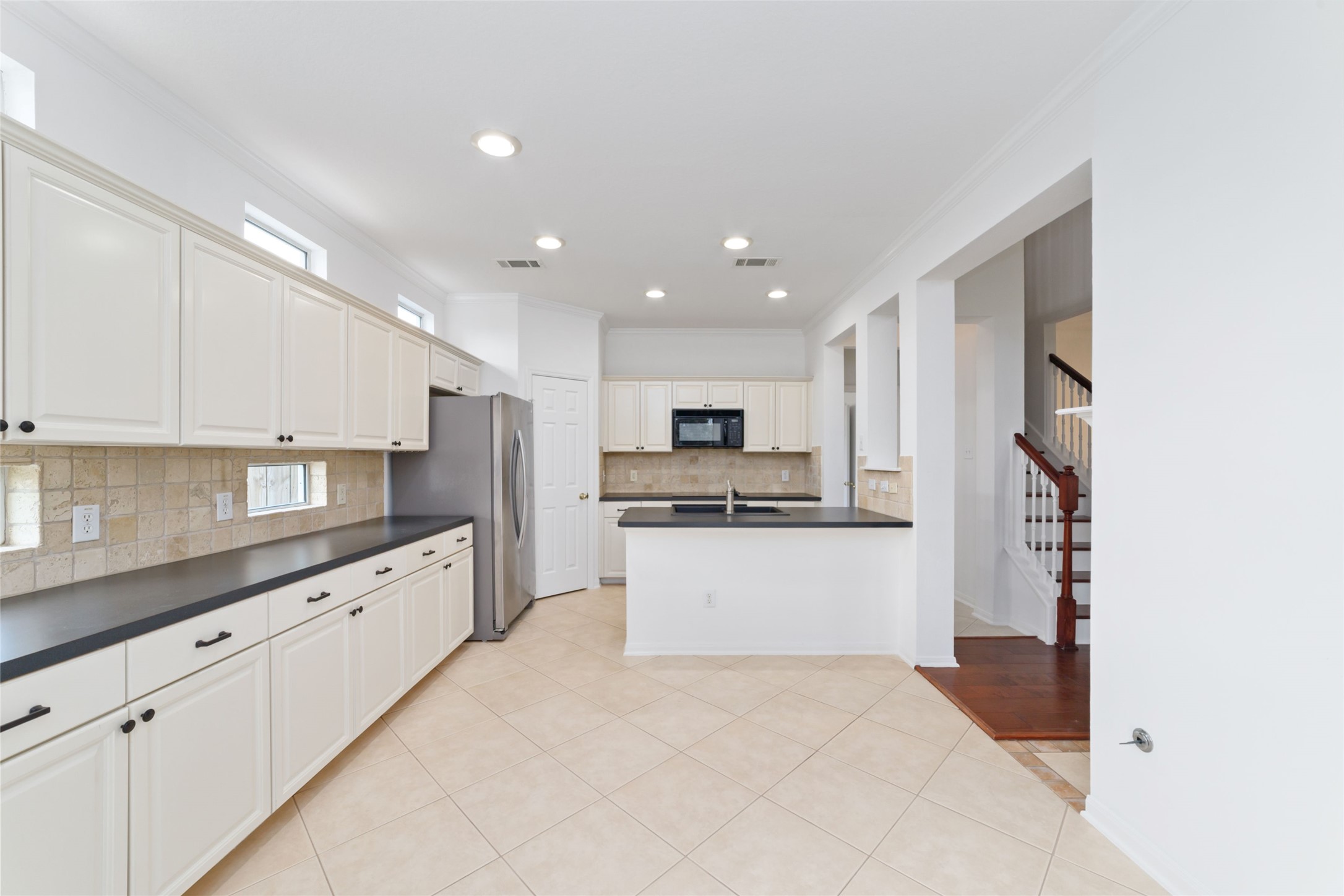 8030 Loyel Pointe Drive Houston, TX 77064 - Photo 11 of 27 a large kitchen with stainless steel appliances kitchen island a sink dishwasher a refrigerator and white cabinets with wooden floor