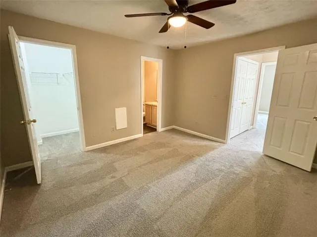 an empty room with a ceiling fan and carpet